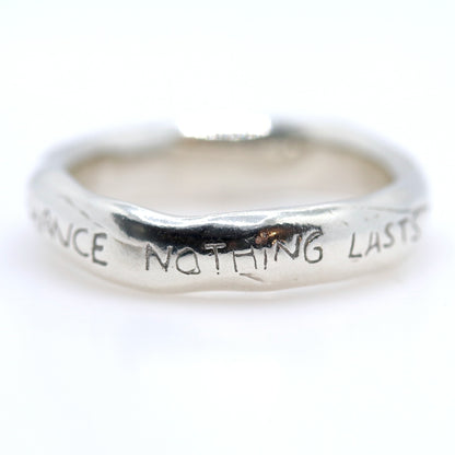Silver ring with engraved text on a white background