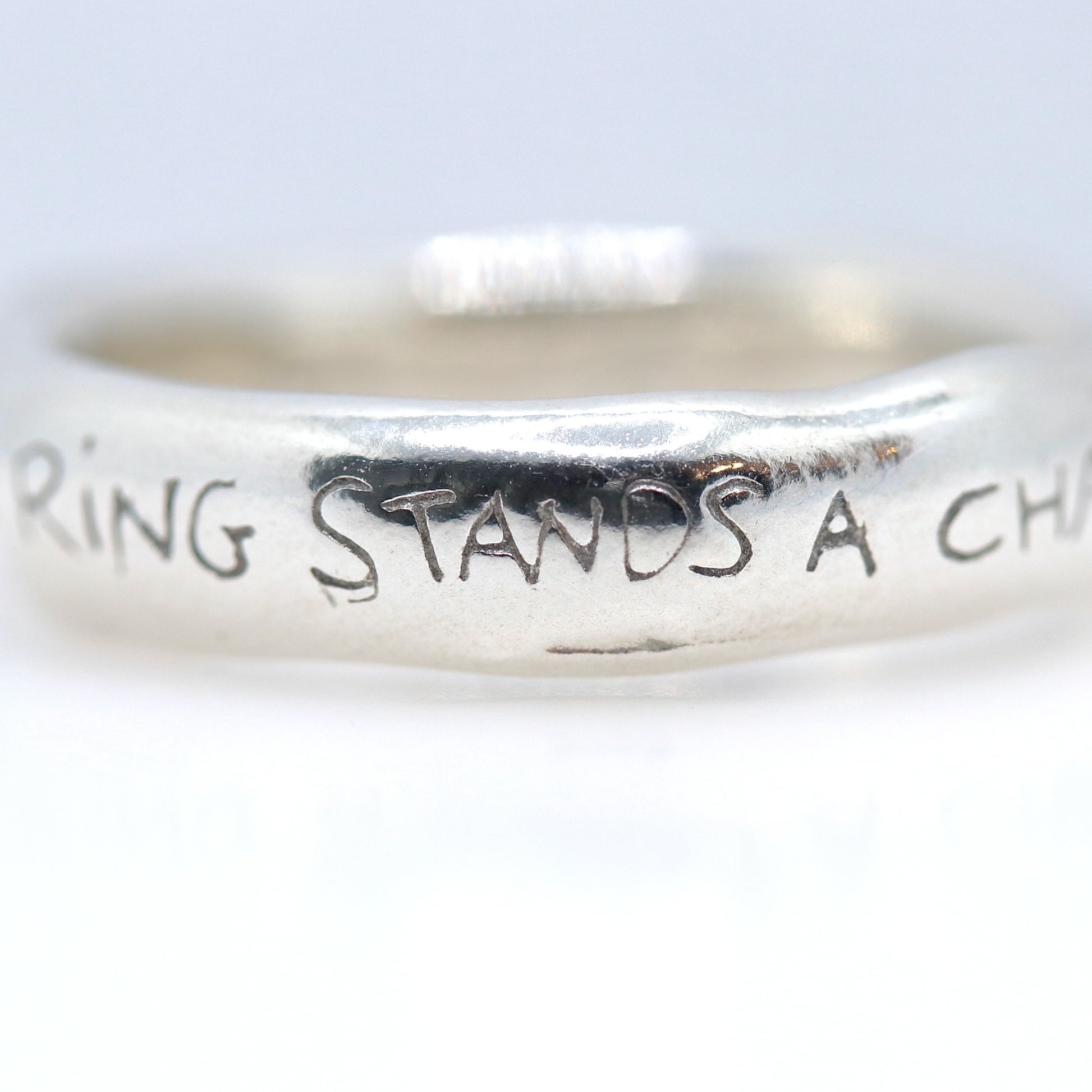 Silver ring with engraved text on a white background