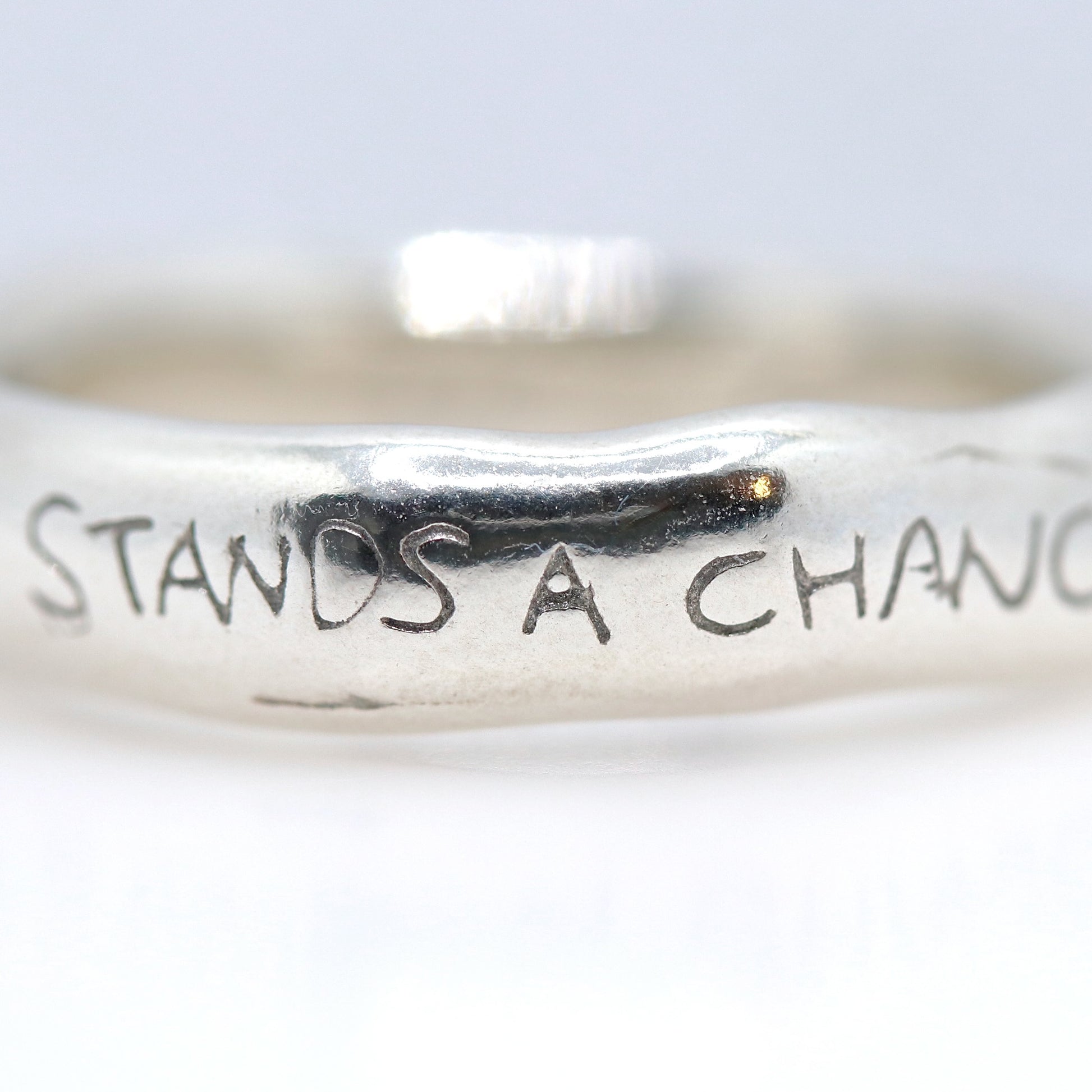 Silver ring with engraved text on a white background