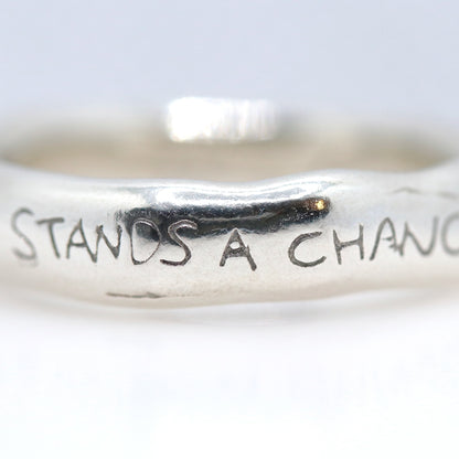 Silver ring with engraved text on a white background