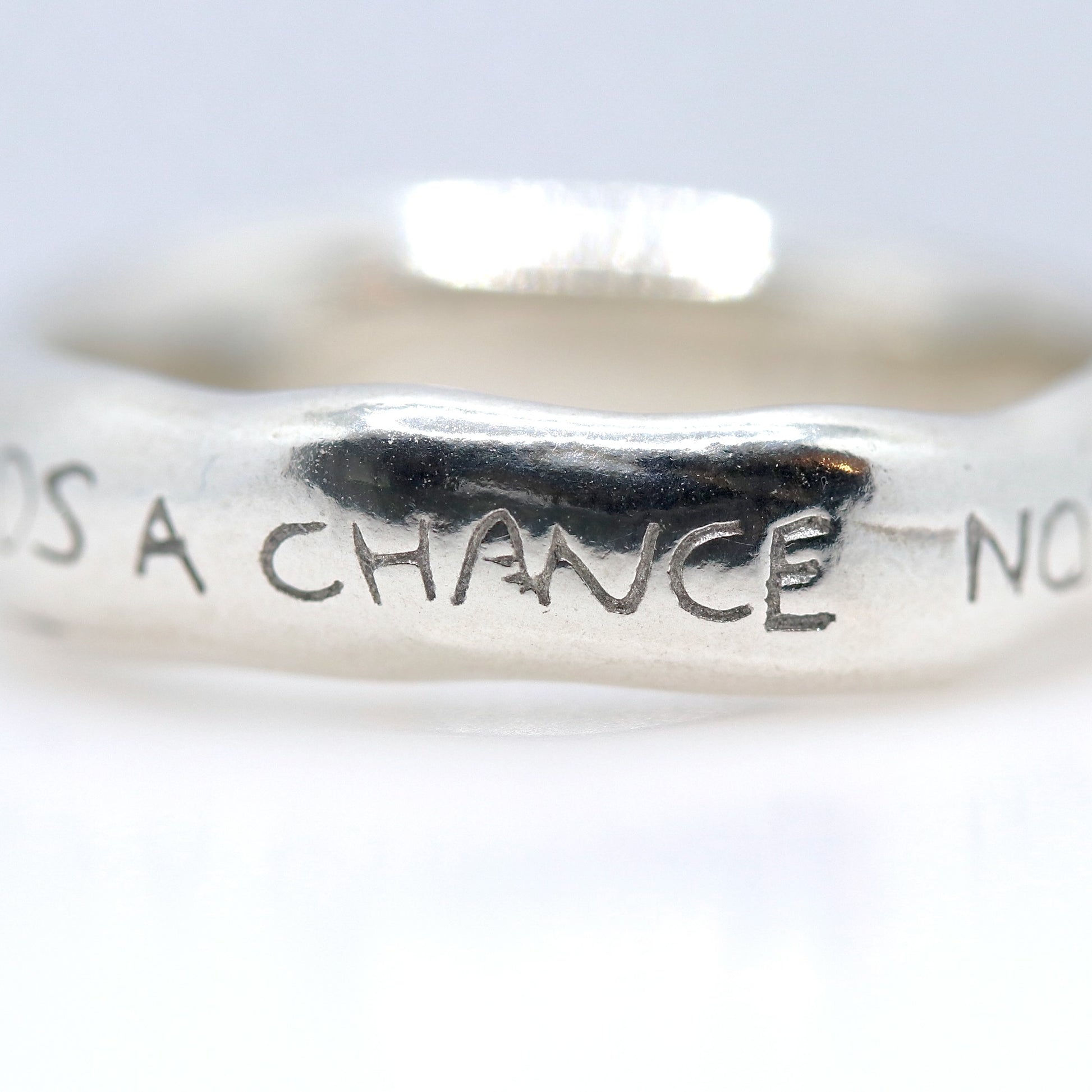Silver ring with engraved text on a white background
