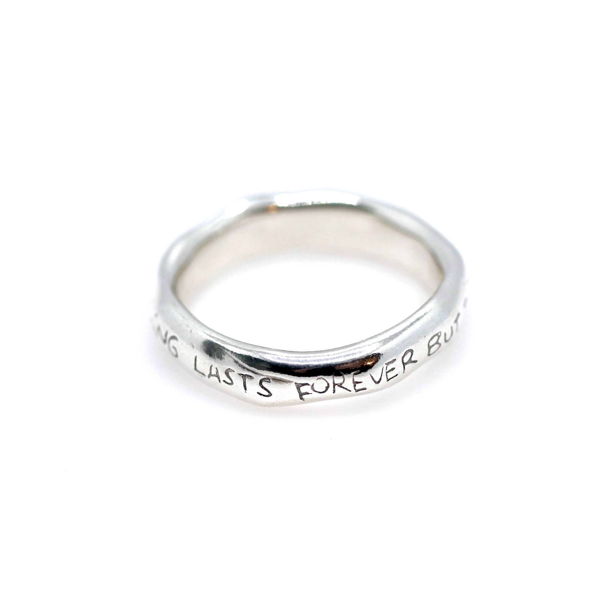 Silver ring with engraved text on a white background