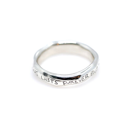 Silver ring with engraved text on a white background