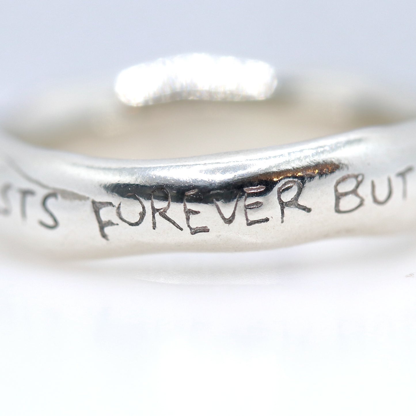 Silver ring with engraved text on a white background