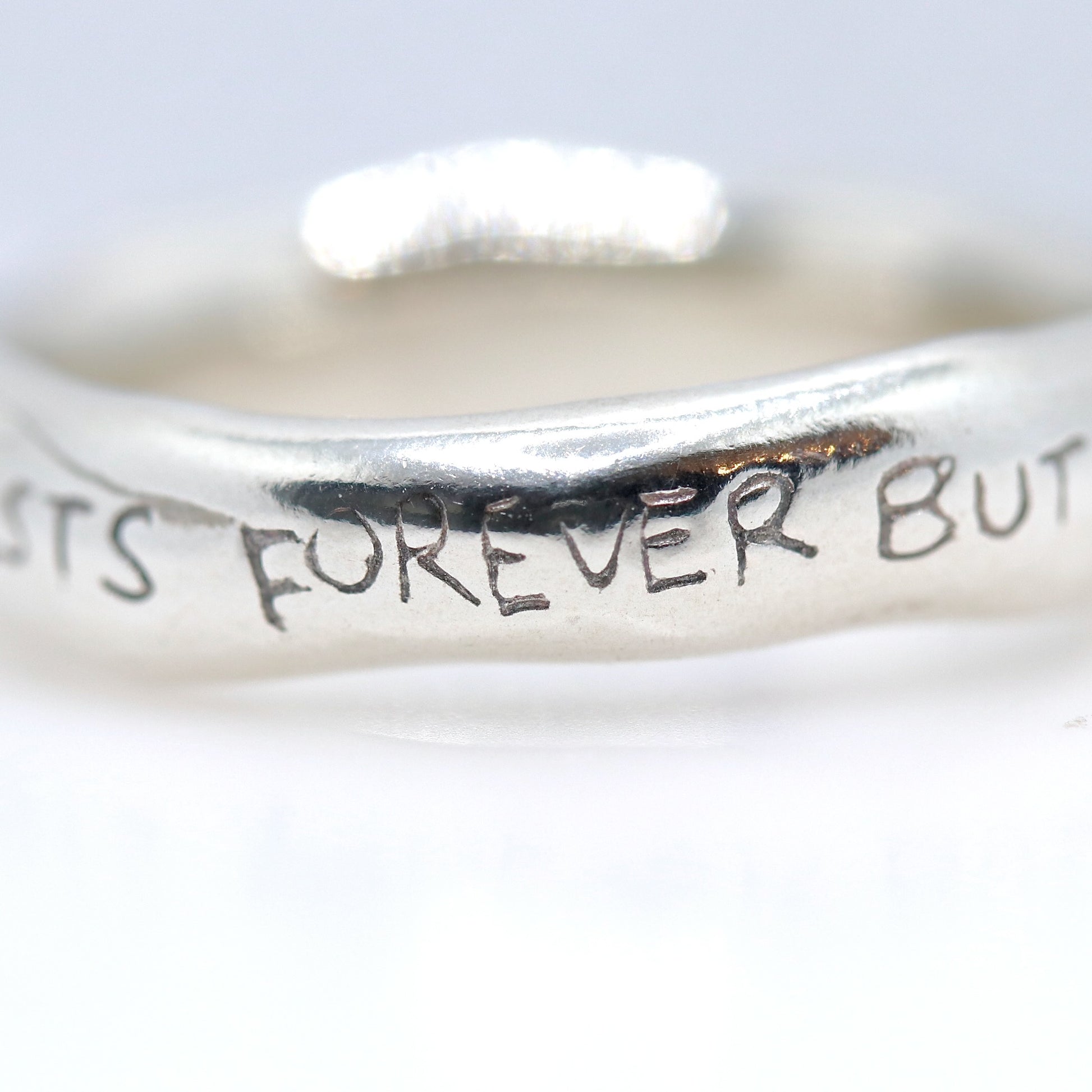 Silver ring with engraved text on a white background
