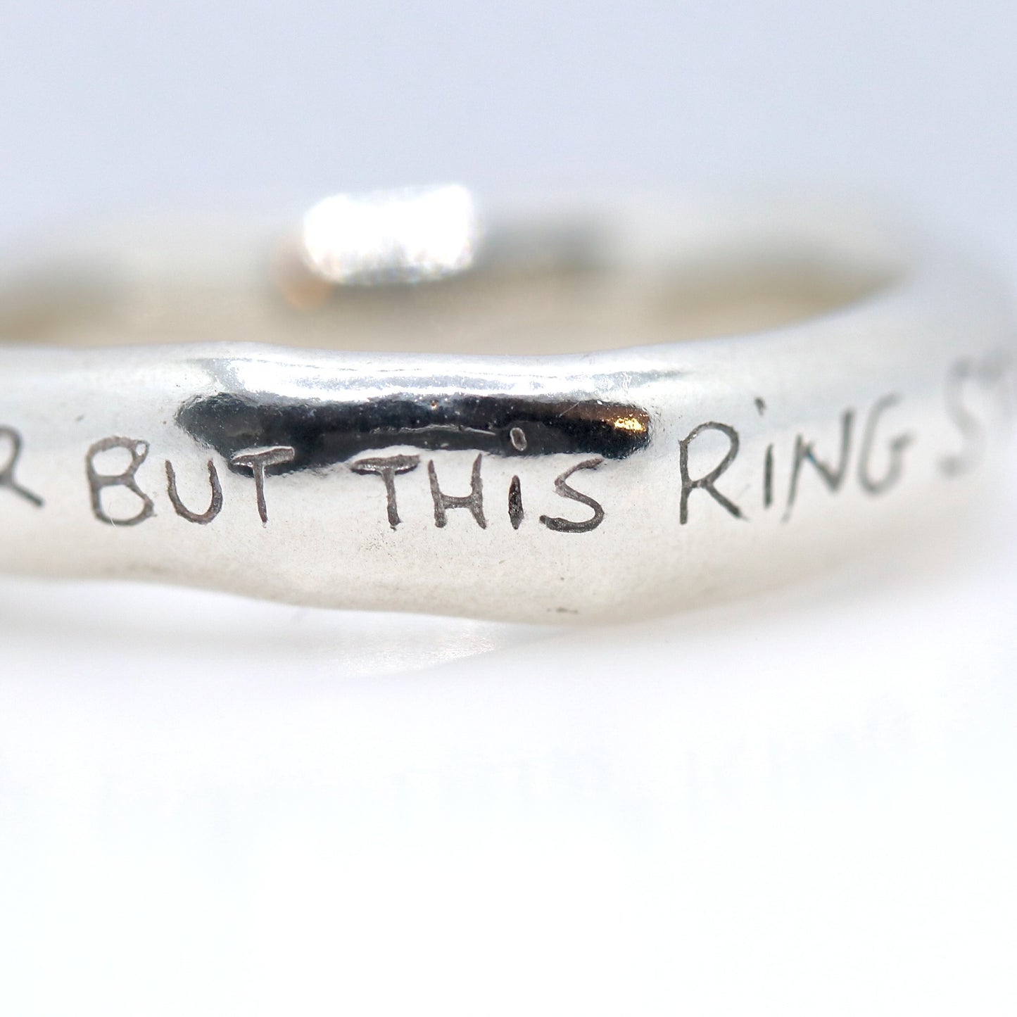 Silver ring with engraved text on a white background