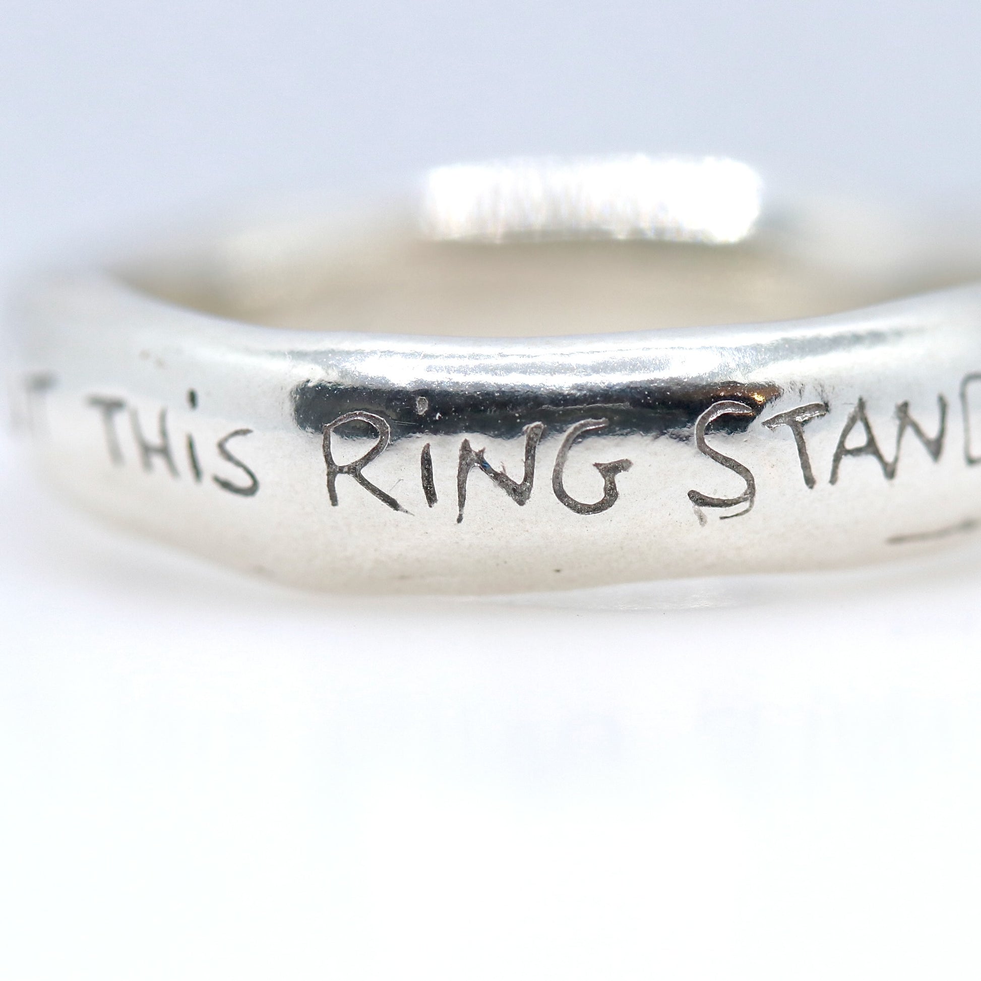 Silver ring with engraved text on a white background