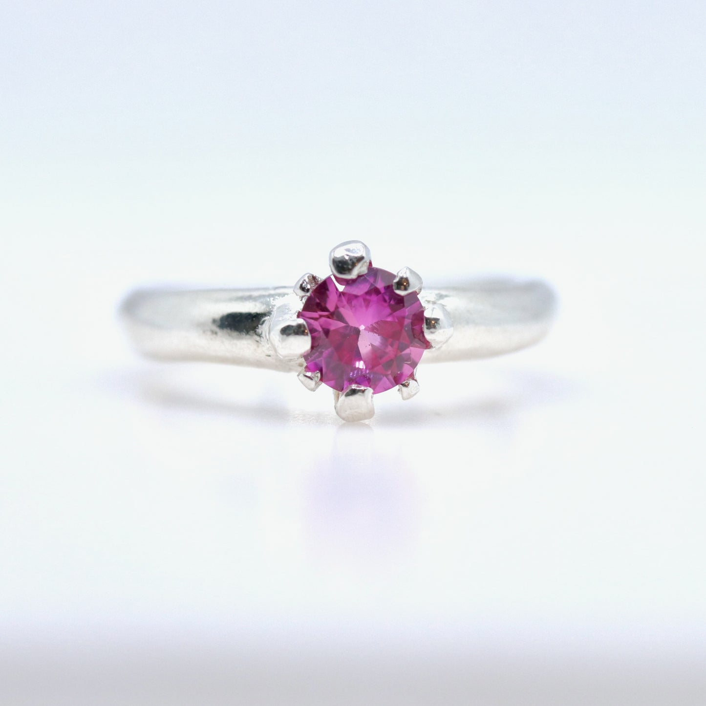 Silver ring with a pink gemstone on a white background