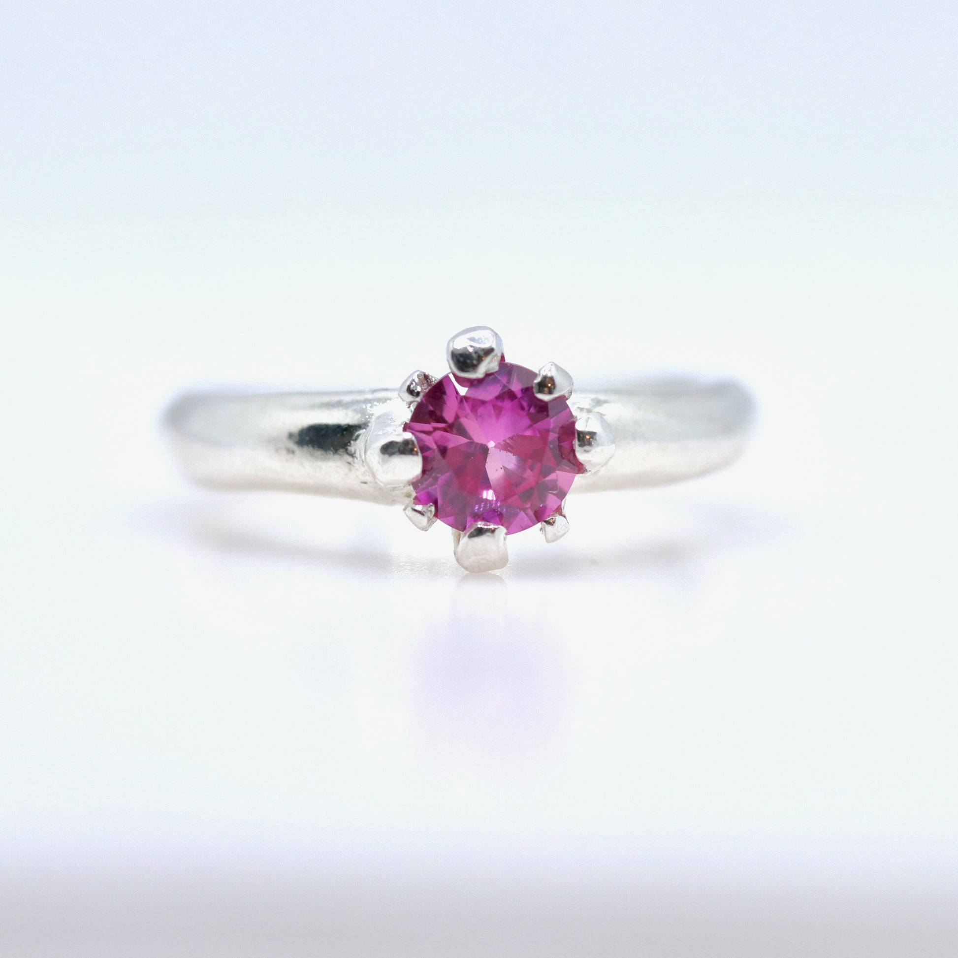 Silver ring with a pink gemstone on a white background