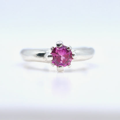 Silver ring with a pink gemstone on a white background