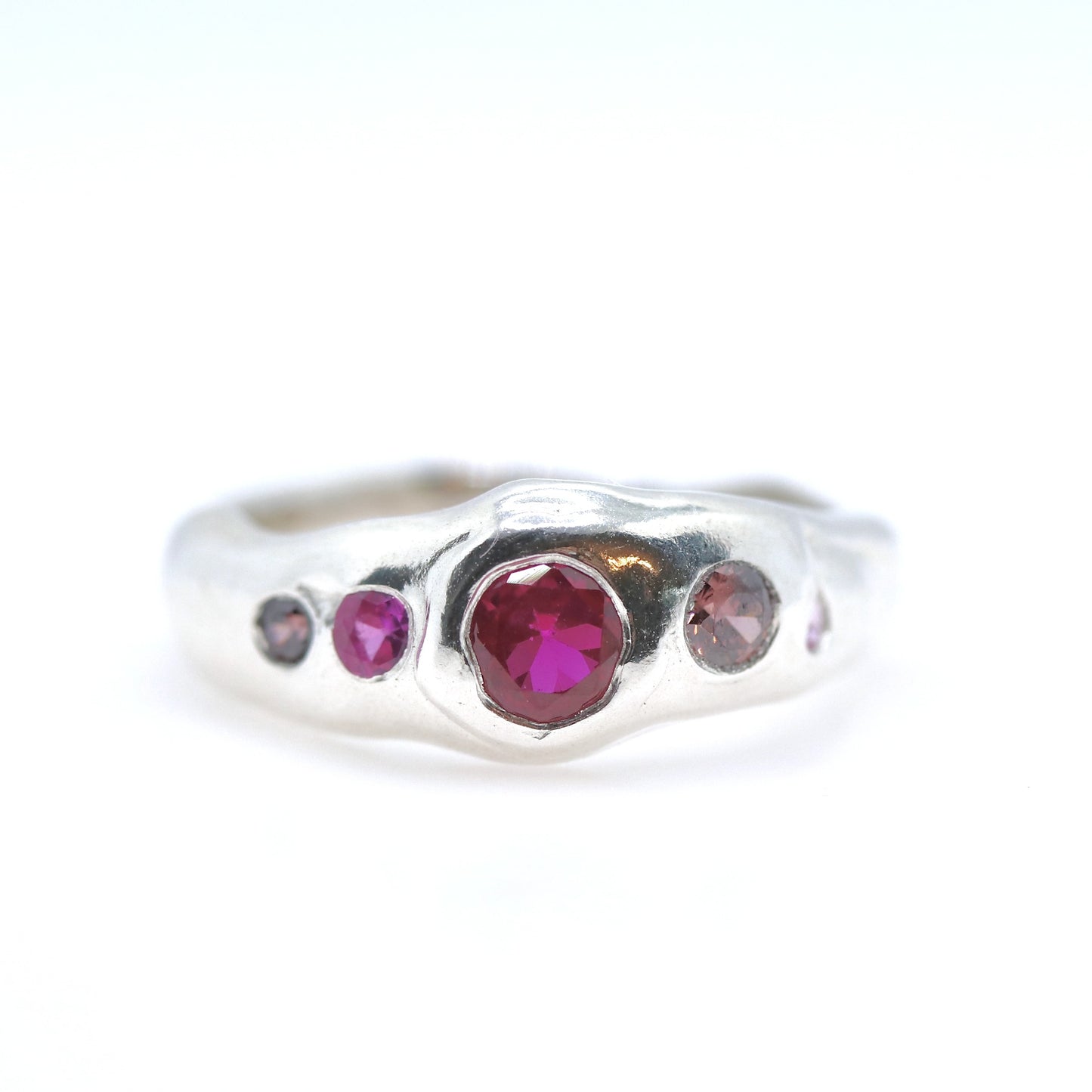 Silver ring with red and pink gemstones on a white background