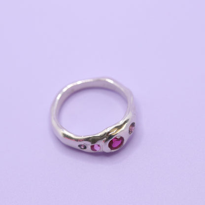 Silver ring with pink gemstones on a light purple background