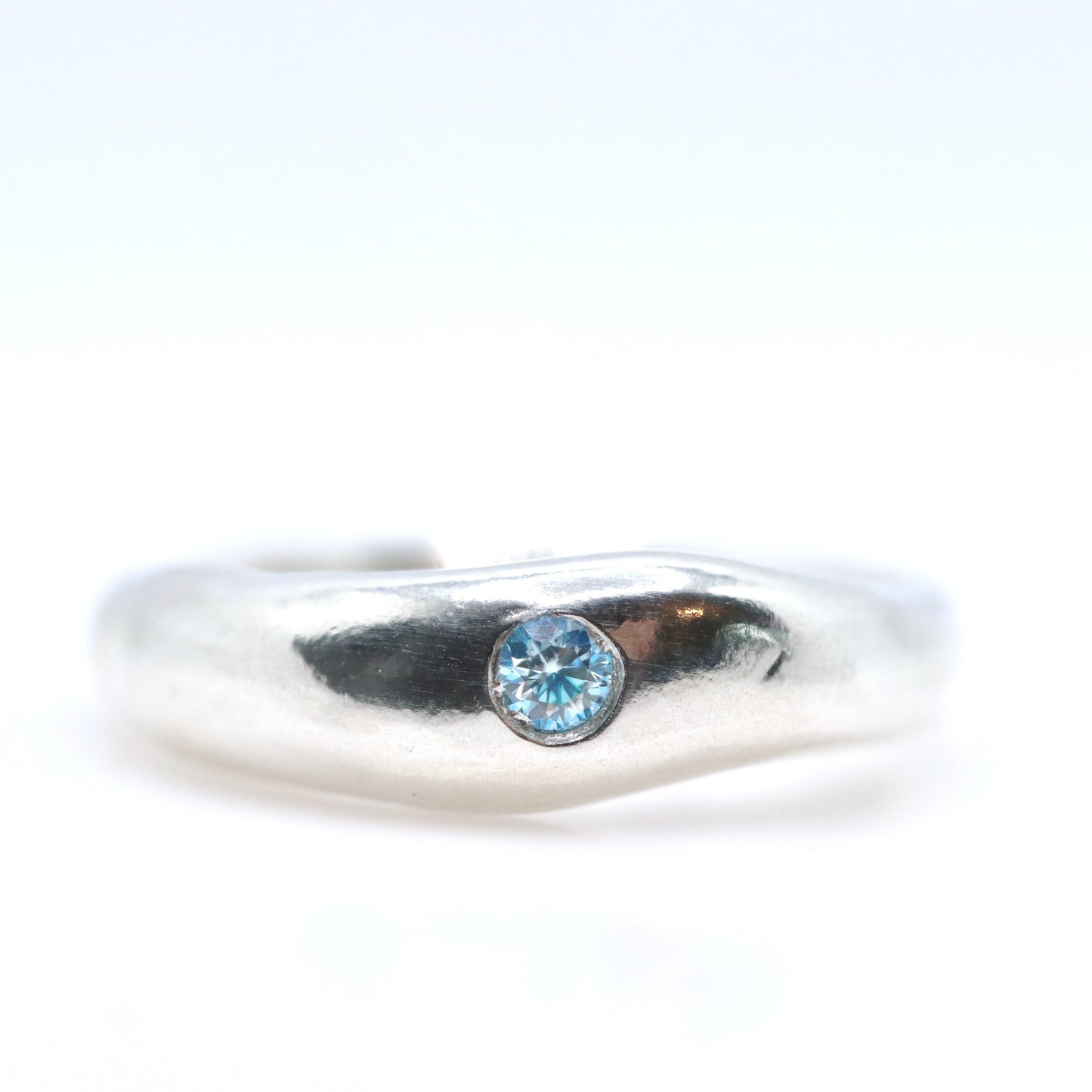 Silver ring with a blue gemstone on a white background