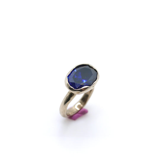 Bronze ring with dark blue oval gem on white background