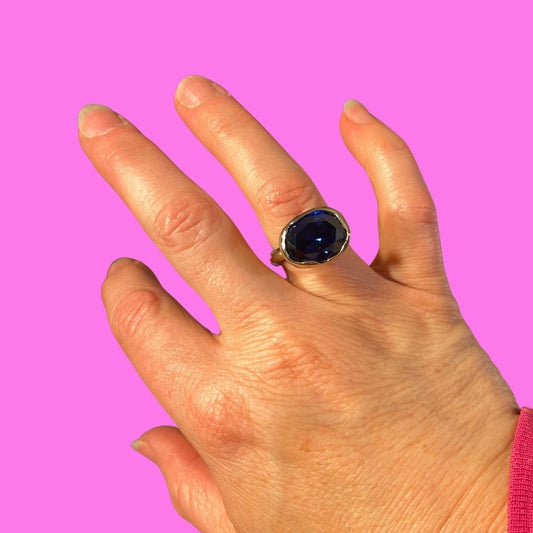 Bronze ring with large dark blue oval on hand with a pink background