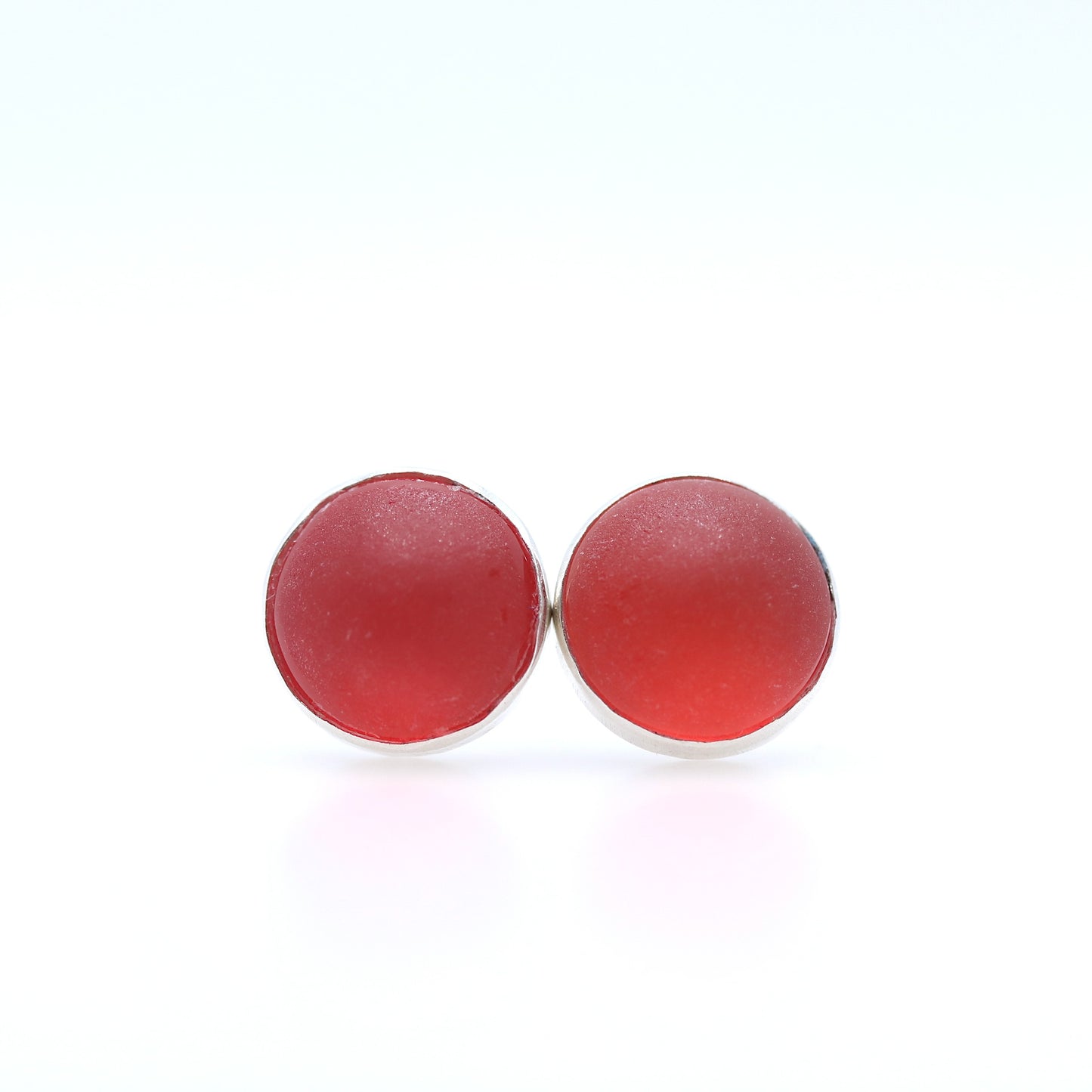 Pair of red round earrings on a white background