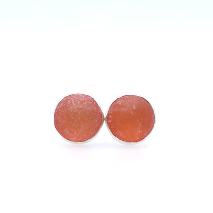 Round earrings with a textured tangerine dome on a white background