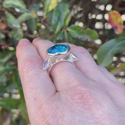 Sterling silver large cocktail ring with bright blue round gem and two lavender square gems on shoulders