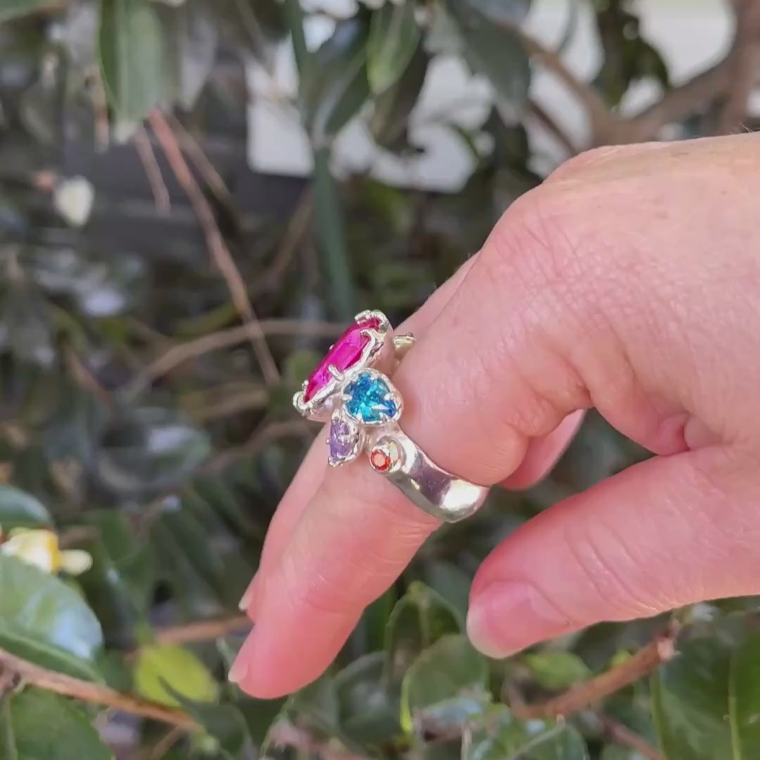 Large silver ring on hand with seven colourful cubic zirconia